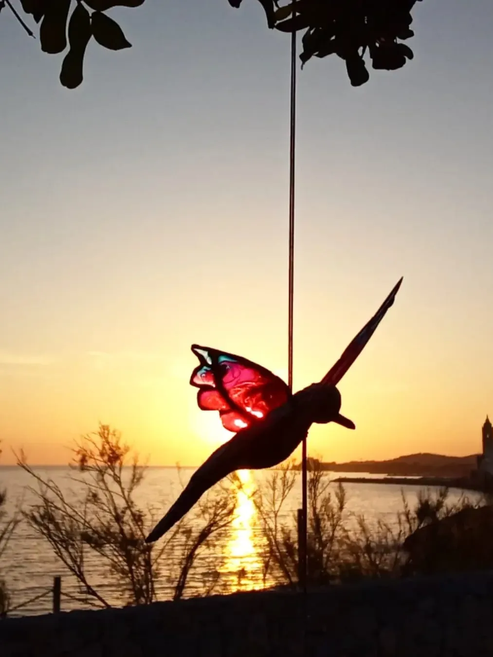 Red bird sculpture silhouetted at golden sunset